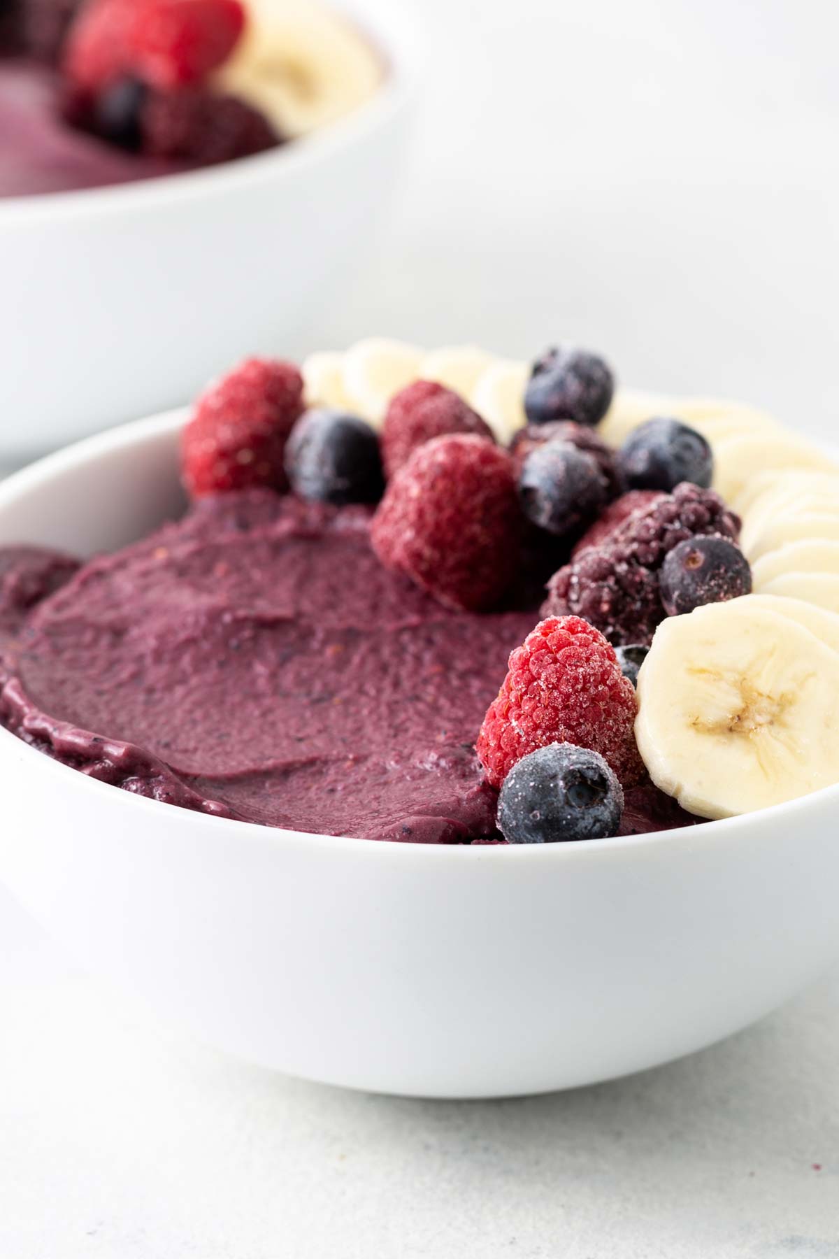 Acai smoothie bowl topped with berries and sliced bananas.