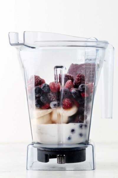 Berries, banana, acai puree and almond milk in a blender.