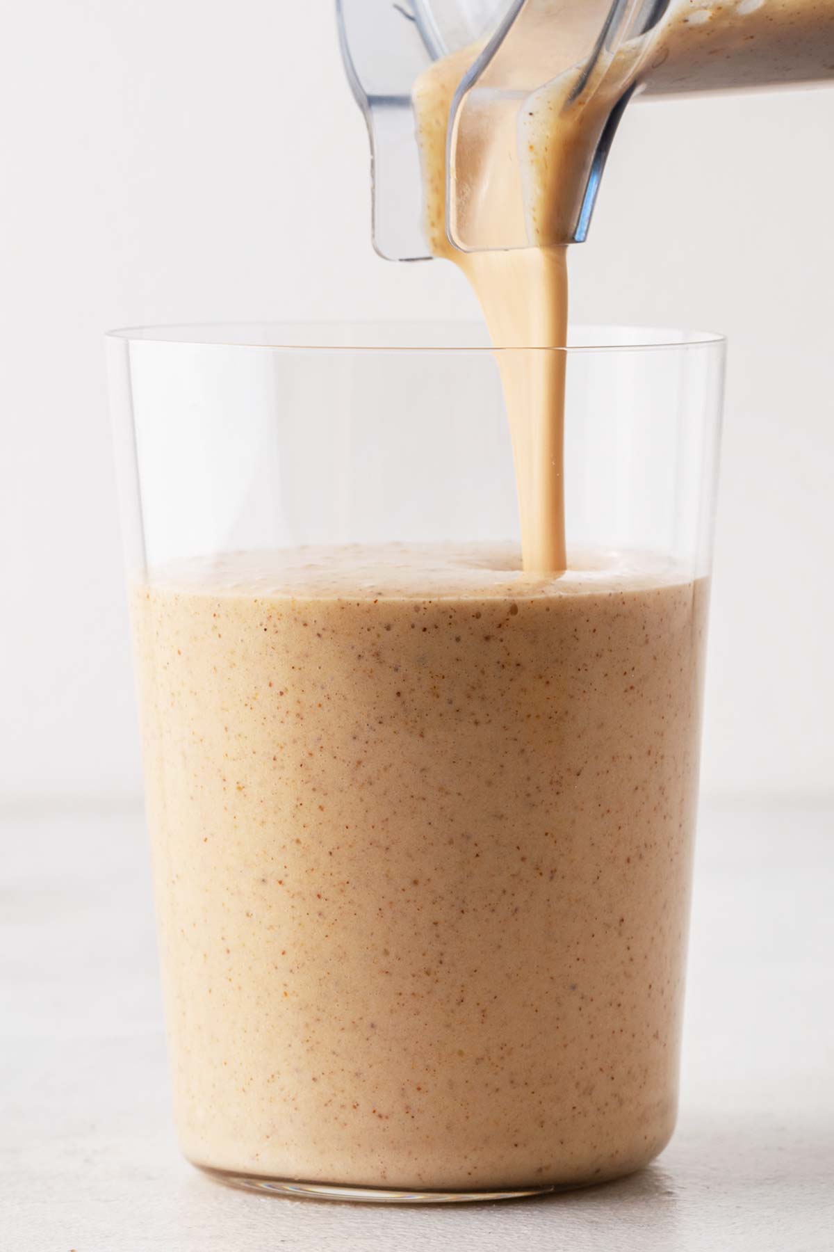 Pouring almond milk smoothie in a cup.