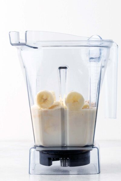 Bananas, date syrup, protein powder, and oat milk in a blender.