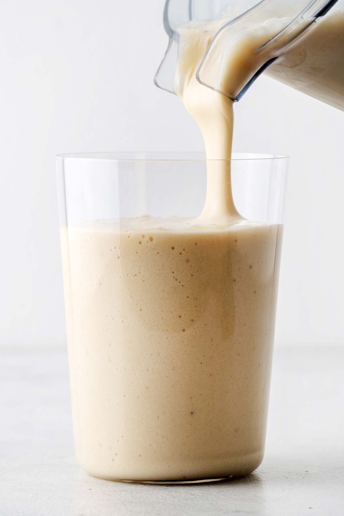 Pouring a banana smoothie in a glass.