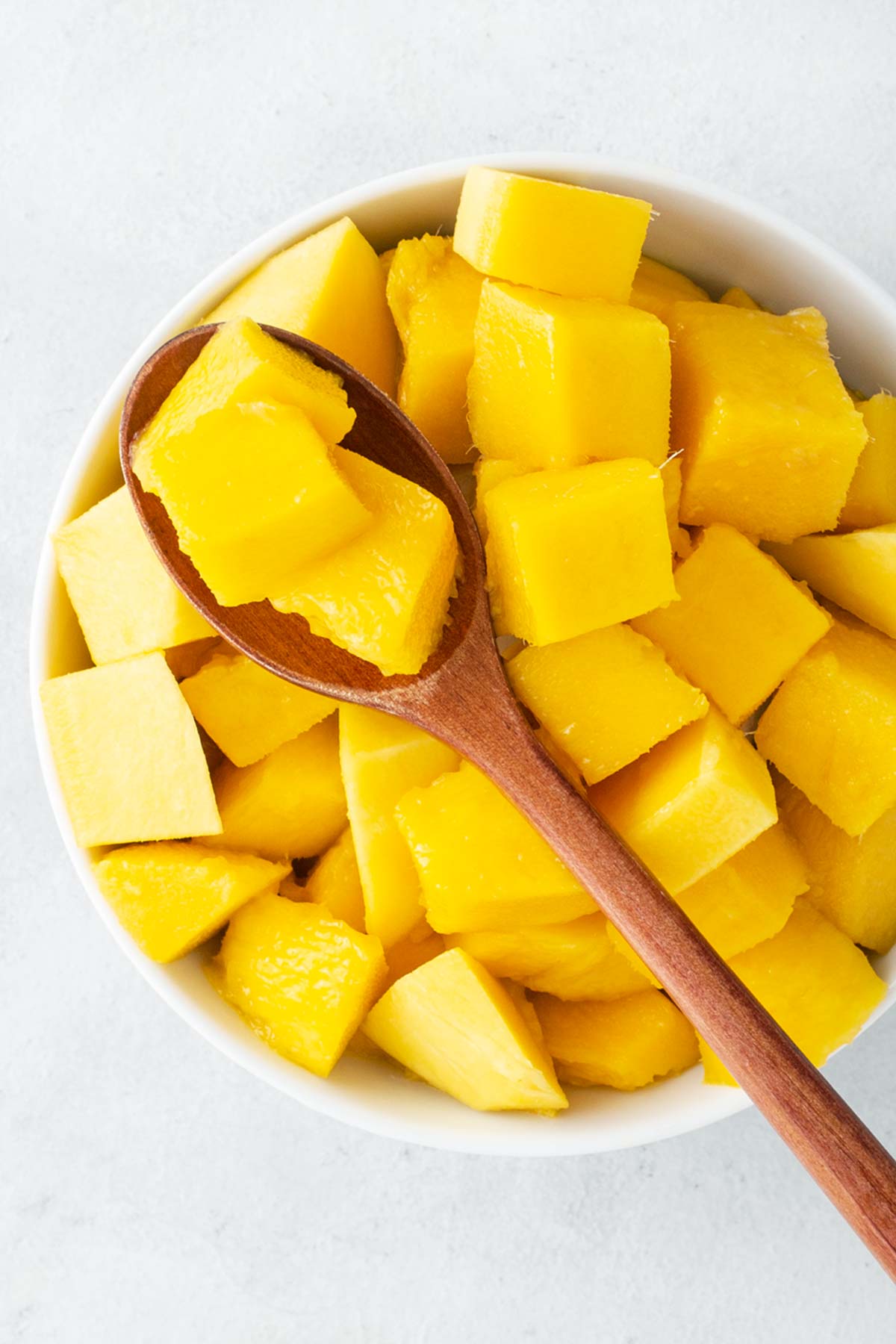 Cut mango cubes in a bowl with a spoon.