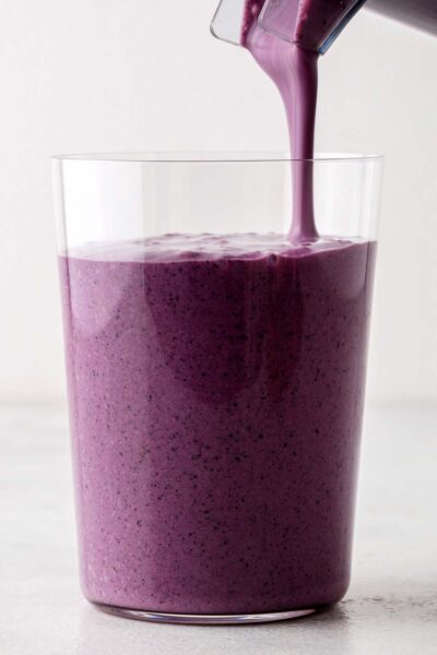 Purple smoothie being poured into a cup. 