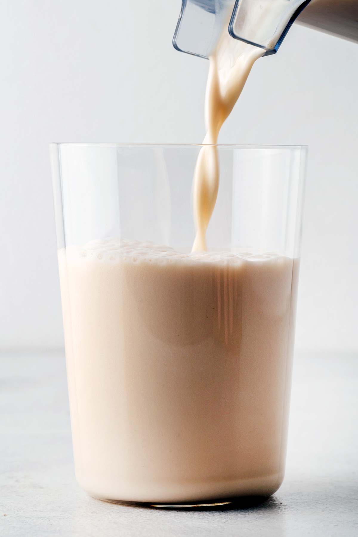 Pouring a caramel protein shake in a glass.