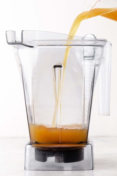 Pouring apple juice into a blender.