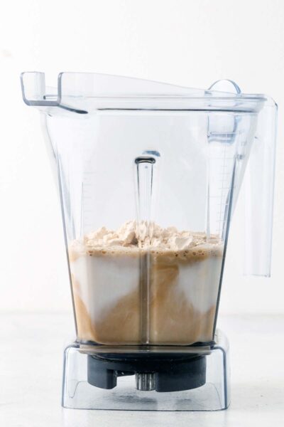 Protein powder, date syrup, coffee, and almond milk in a blender. 