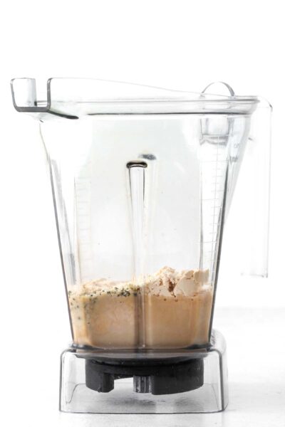 Protein powder, hemp seeds, coffee, and oat milk in a blender.