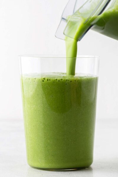 Green smoothie being poured into a cup. 