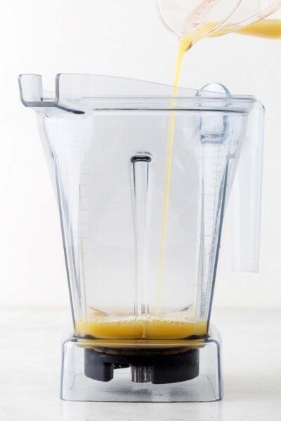 Pineapple juice being poured into a blender. 