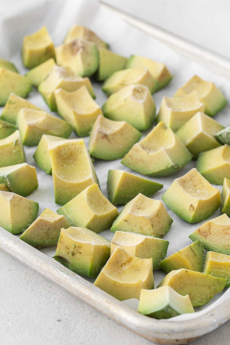 Frozen pieces of avocado on a cookie sheet.