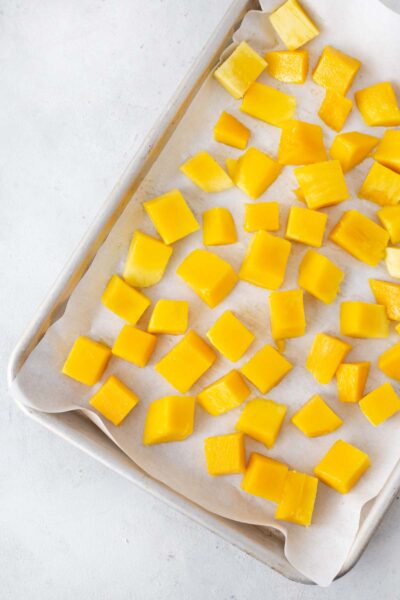 Cubed mangos on a baking sheet.