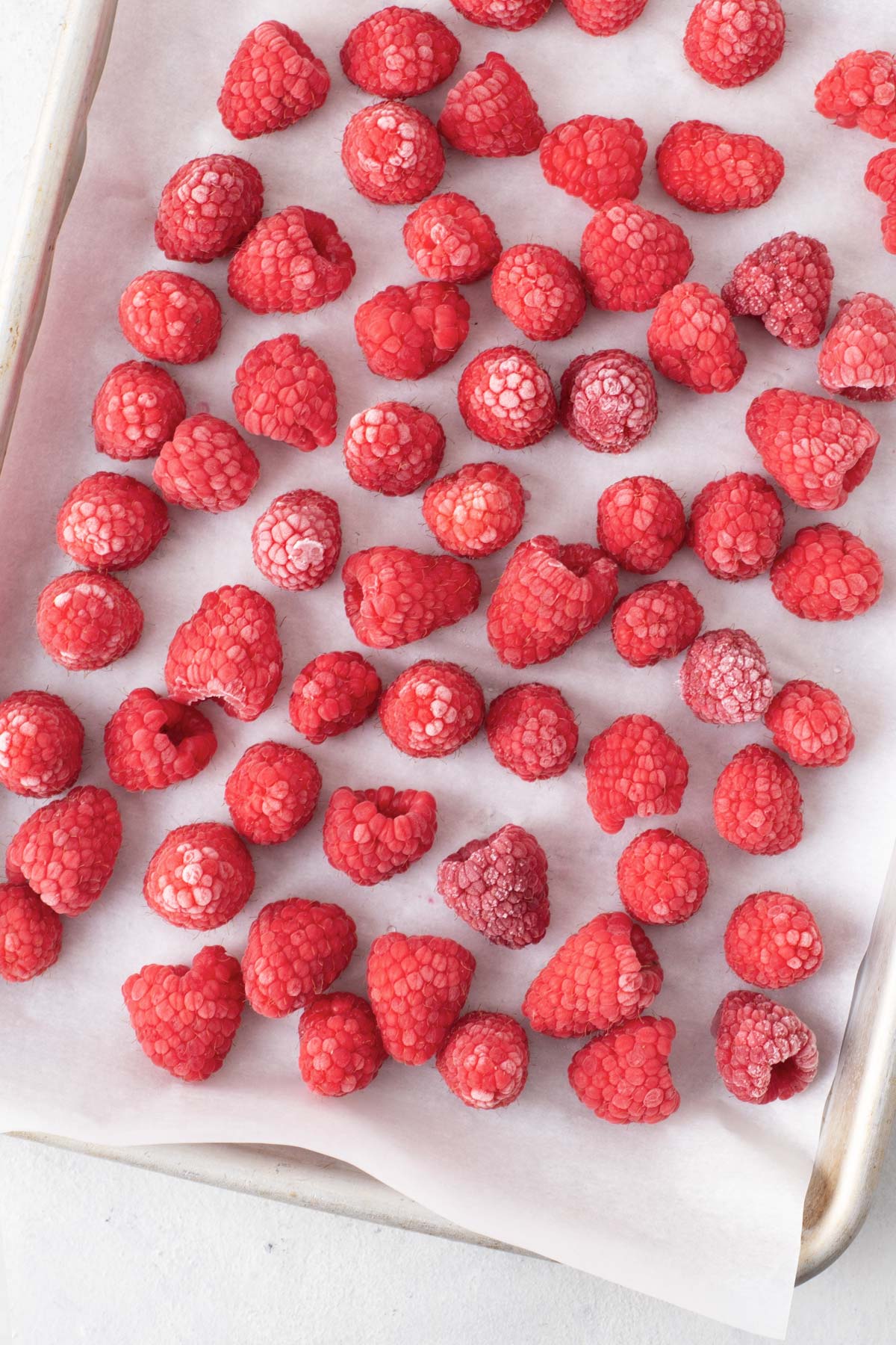 Frozen raspberries on a baking sheet.
