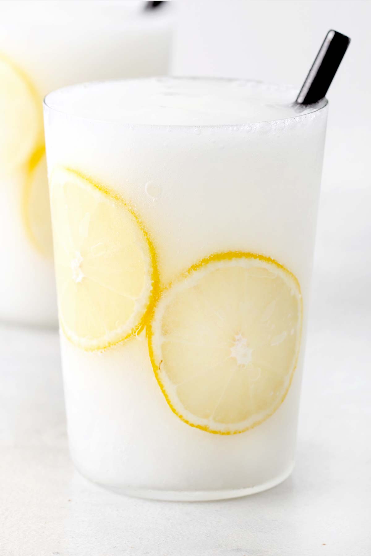 Frozen lemonade in a glass with a black straw.