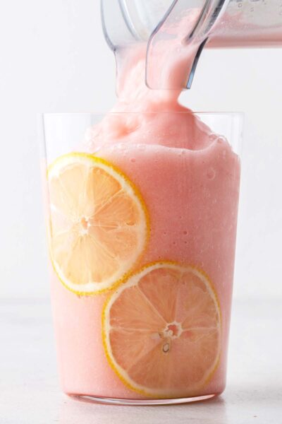 Pouring Frozen Strawberry Lemonade into a cup from a blender.