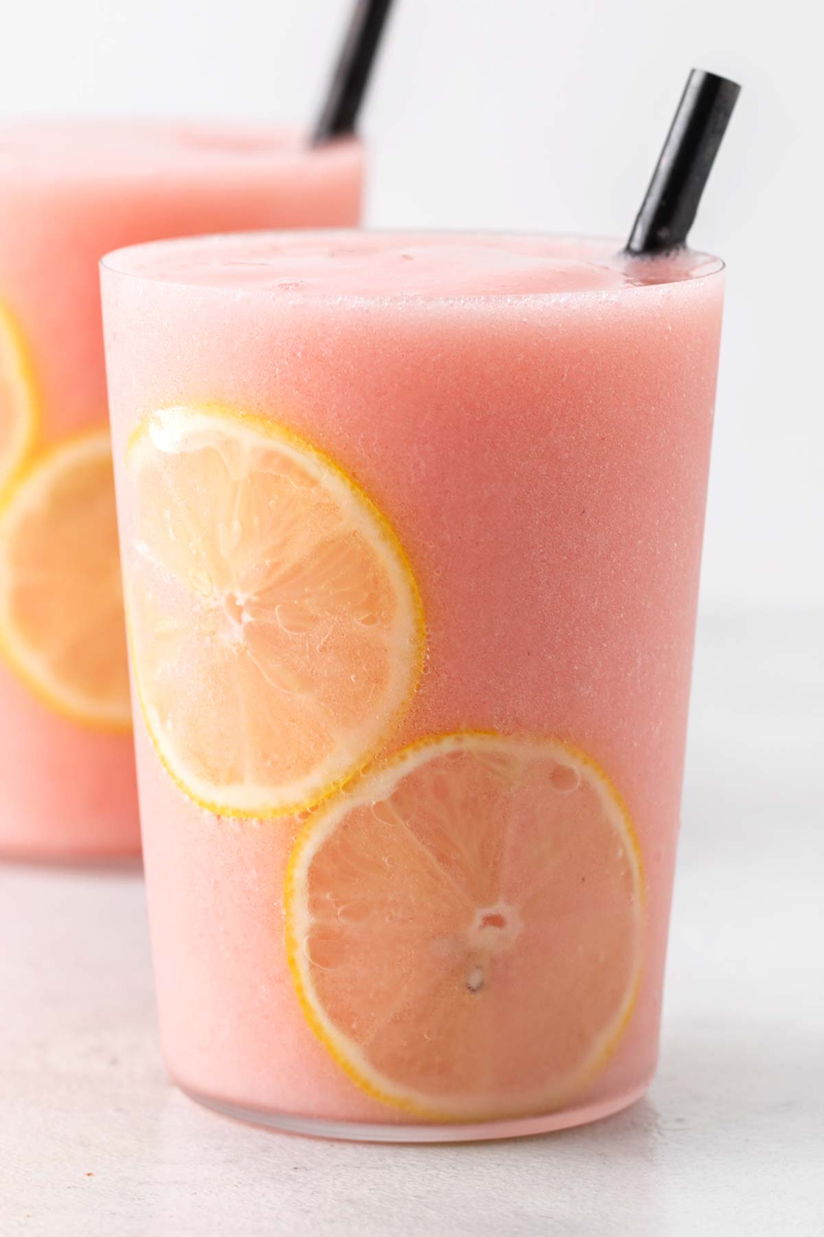 Frozen strawberry lemonade in a glass with a black straw.