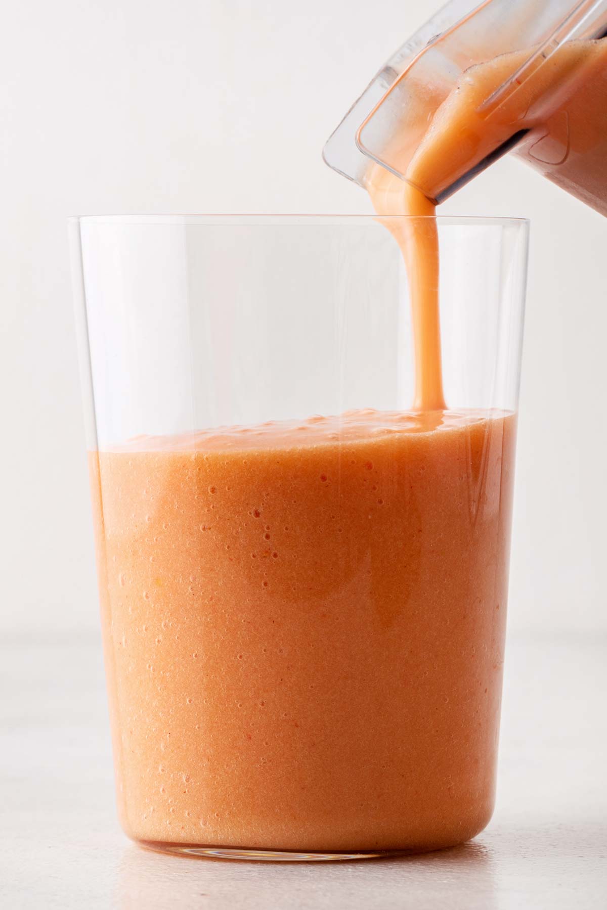 Pouring fruit smoothie in a glass.