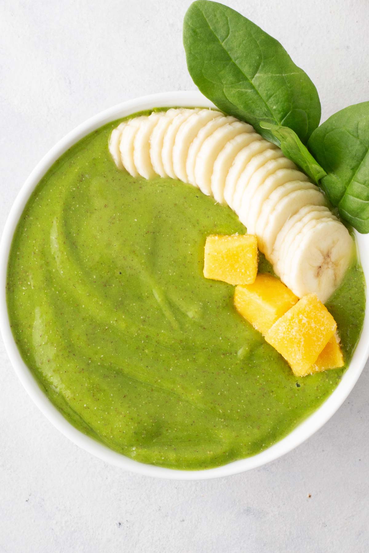 Green smoothie bowl on a gray table.