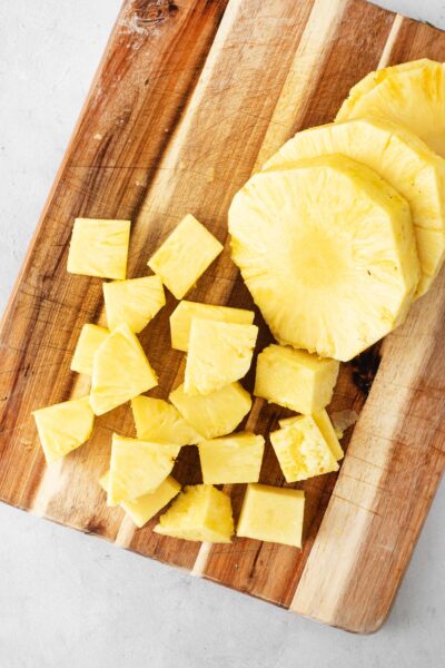 Pineapple rounds and cubes on a wooden cutting board.