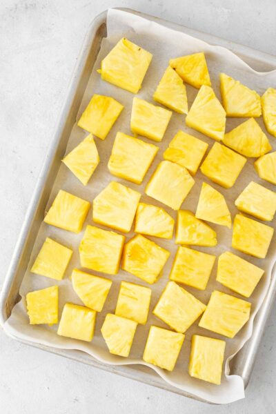 Pineapple cubes on a baking sheet lined with parchment paper.