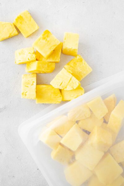 Frozen pineapple cubes in a reusable silicone storage bag.