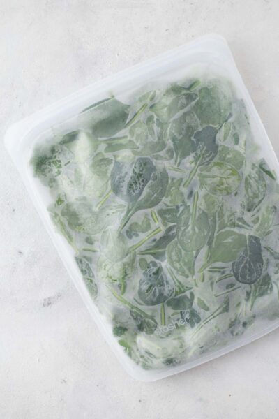 Frozen baby spinach in a reusable silicone storage bag.