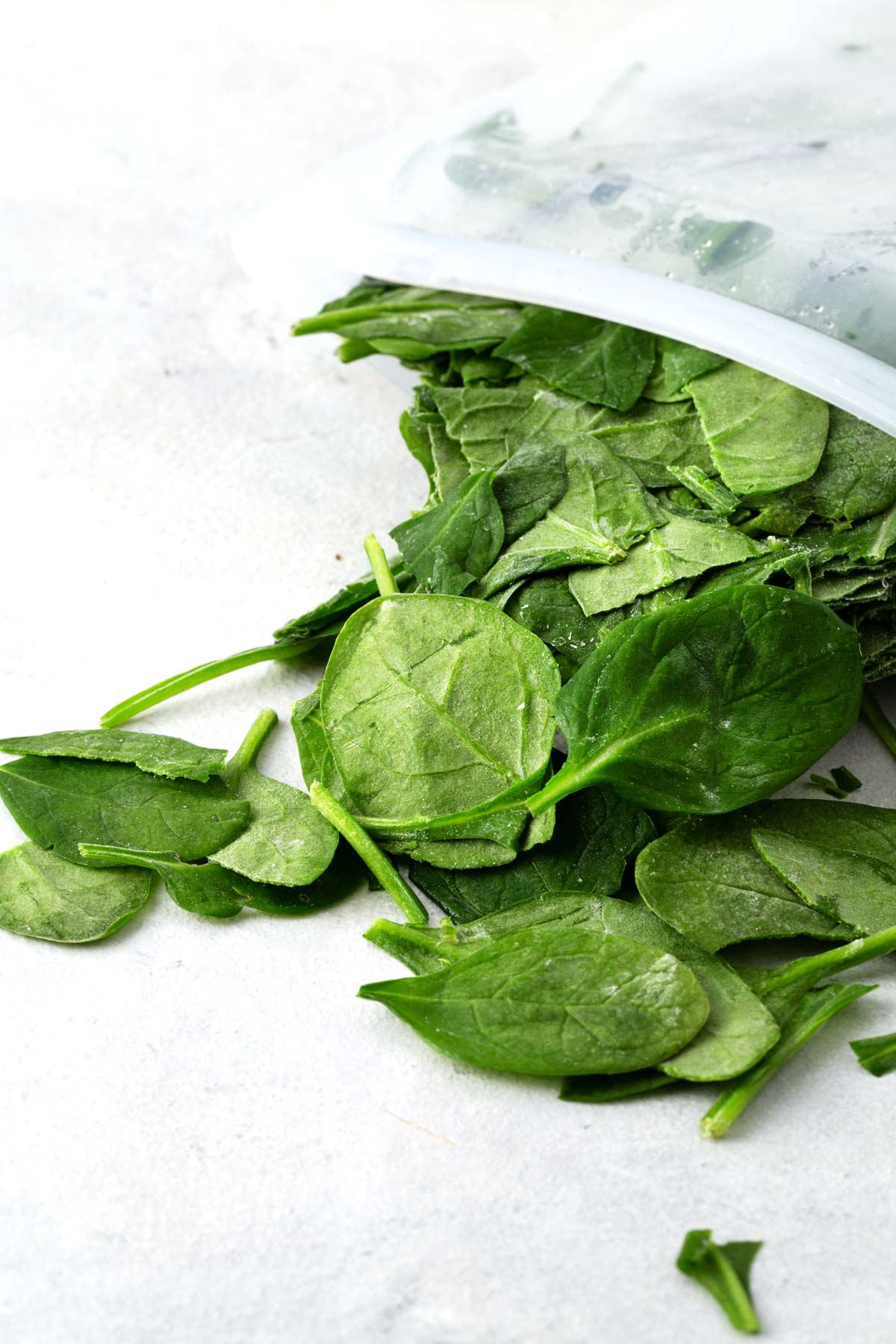 Frozen baby spinach on a gray table.