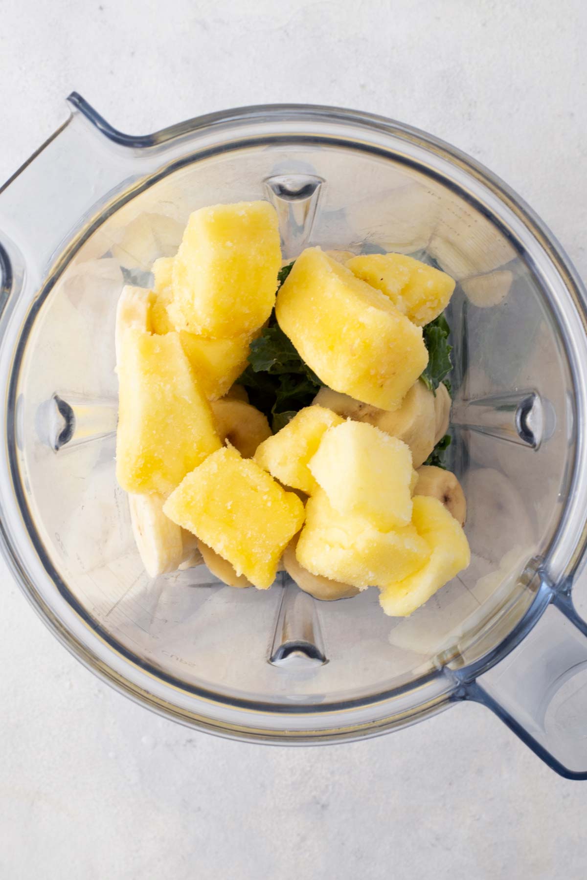 Kale pineapple smoothie ingredients in a blender.
