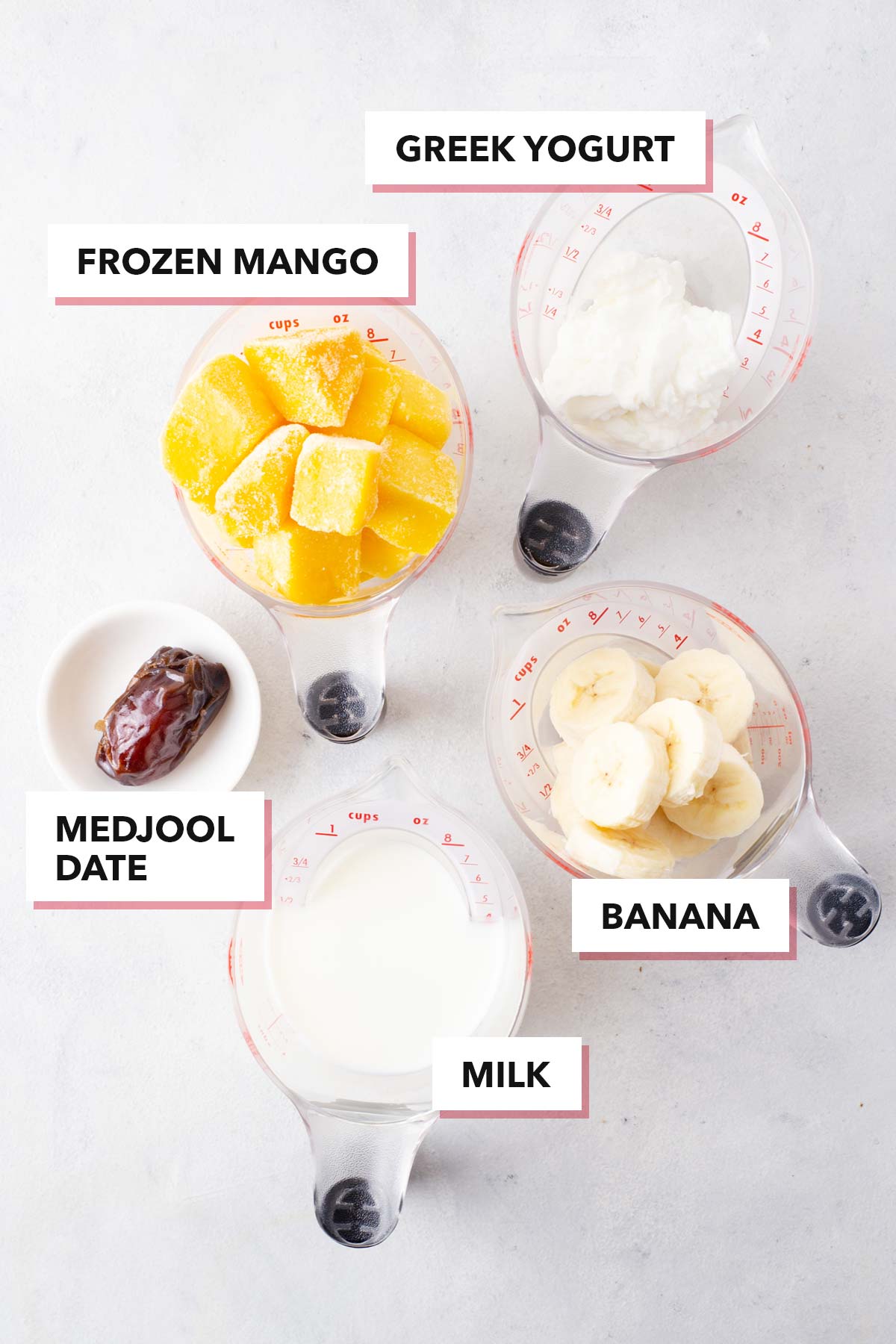 Ingredients to make a mango yogurt smoothie on a table.