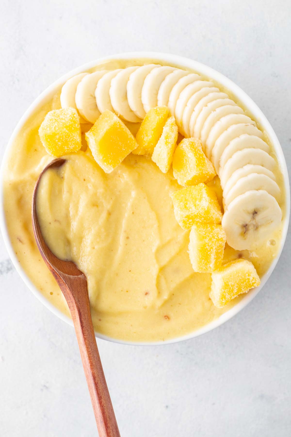 Mango smoothie bowl with a wooden spoon.