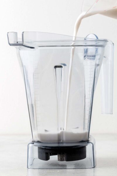 Coconut milk being poured into a blender. 