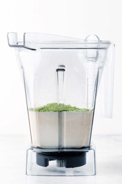 Matcha and oat milk in a blender.