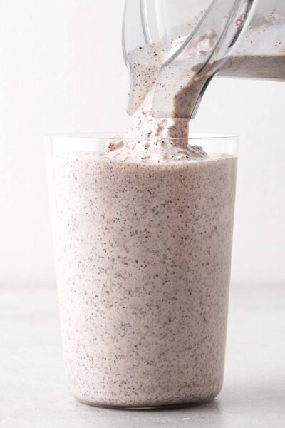Pouring a mint chocolate chip milkshake in a glass.