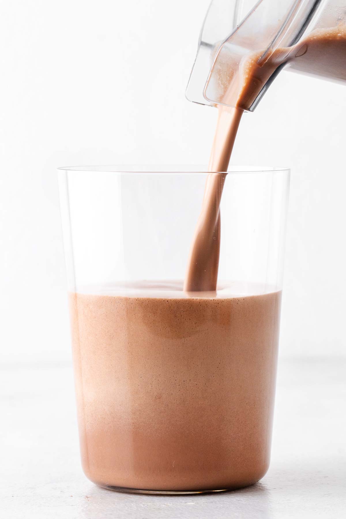 Pouring a mocha protein shake in a glass.