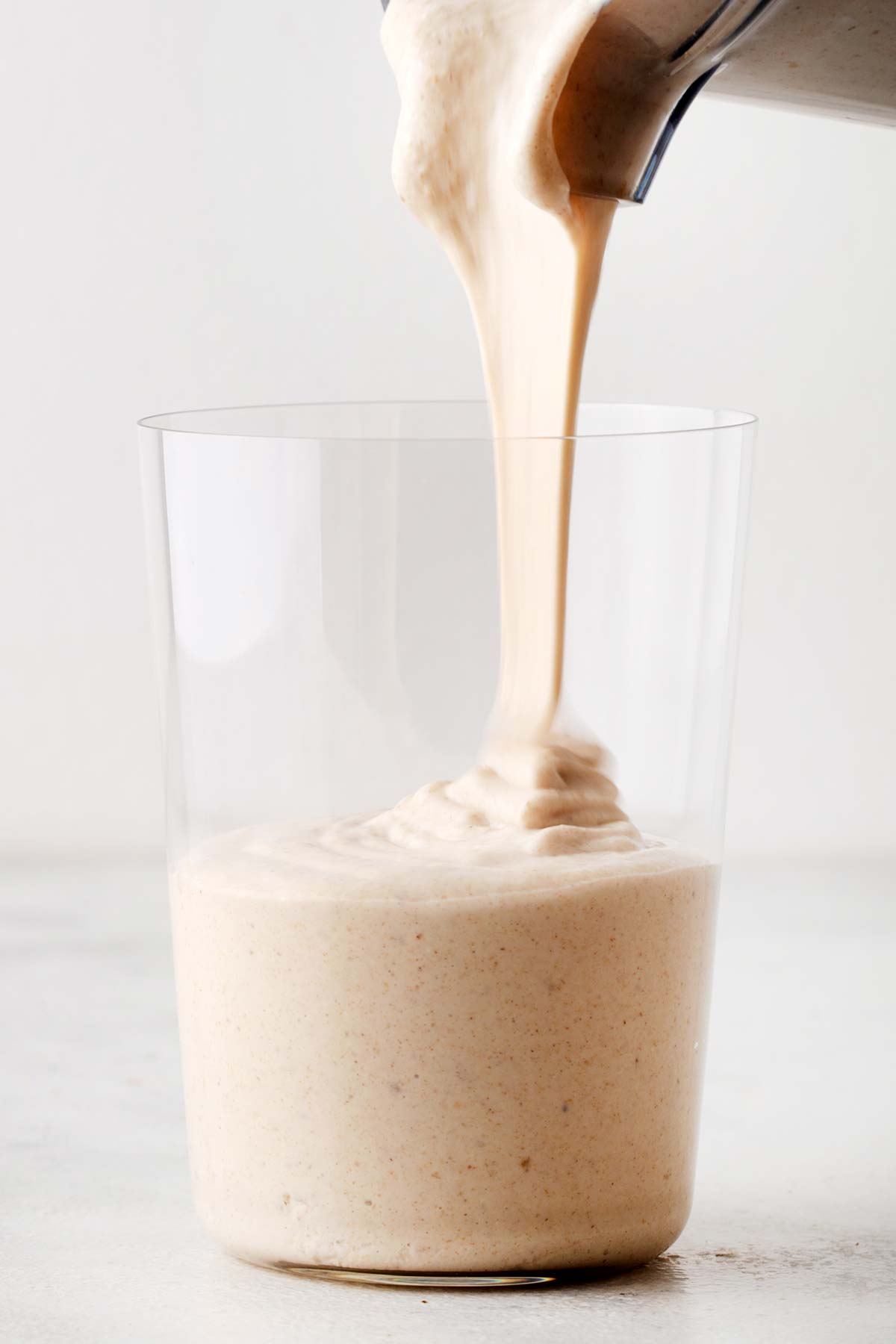 Pouring oatmeal smoothie in a cup.