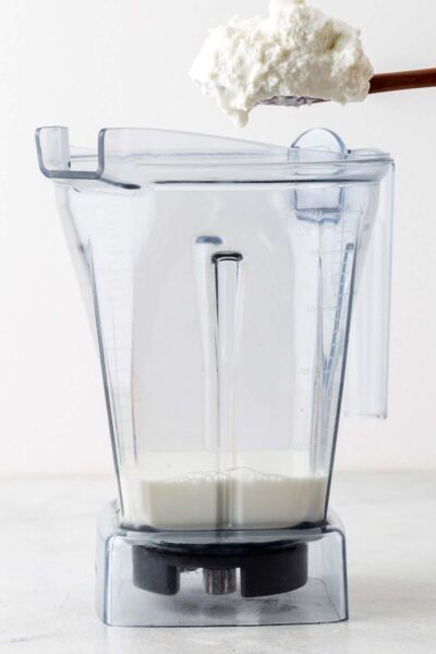 Yogurt added to a blender with milk. 