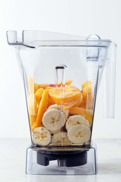 Chia seeds in a blender with white grape juice, banana, and frozen peach wedges.