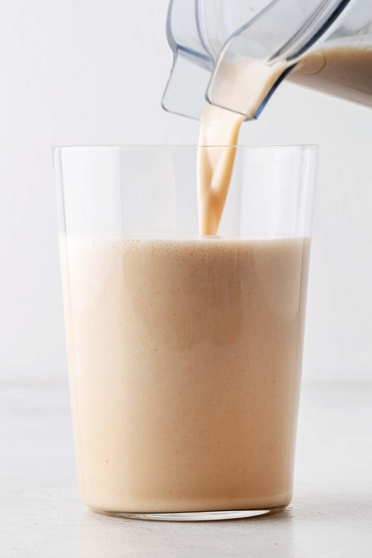 Pouring a peanut butter protein shake in a glass.