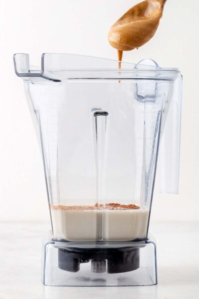 Peanut butter added to blender with oat milk and cinnamon.