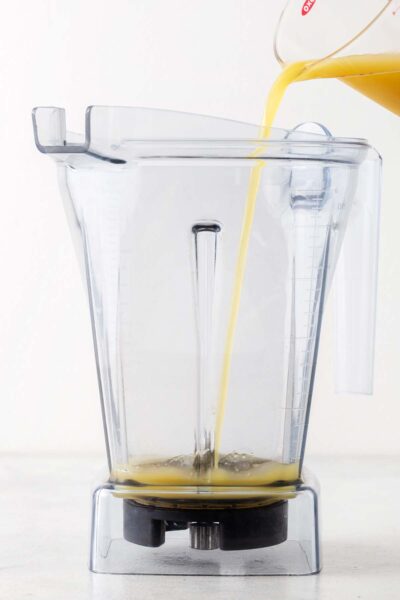 Pineapple juice being poured into a blender. 