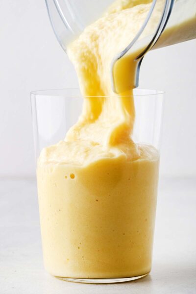 Pineapple smoothie being poured into a cup.