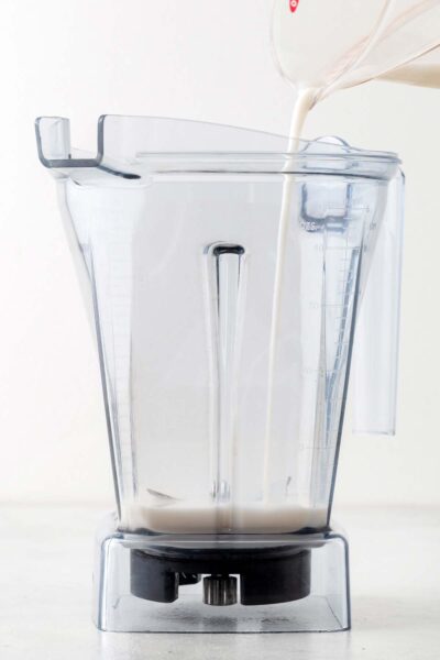 Pouring almond milk into a blender.