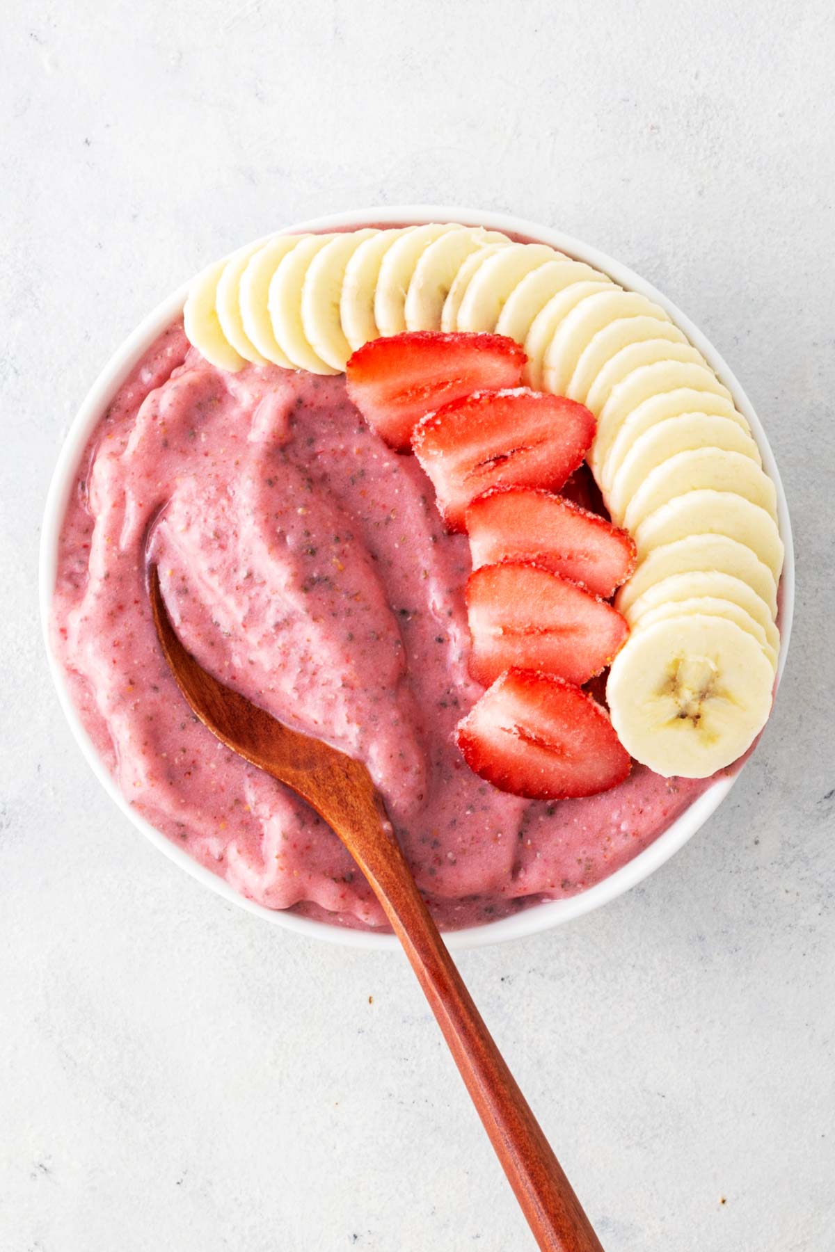 Strawberry banana smoothie bowl on a gray table.