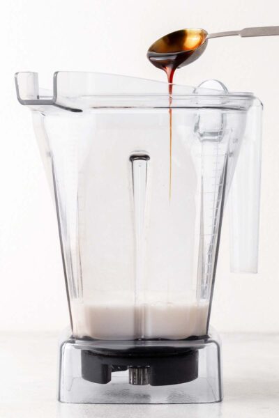 Date syrup poured into a blender with almond milk. 