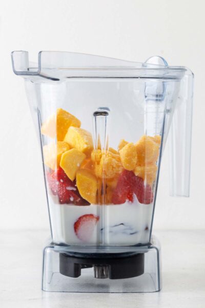 Mango, strawberry, date, yogurt, and milk in a blender. 
