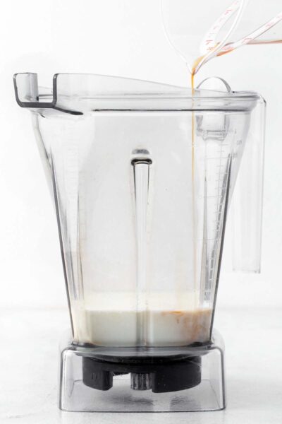 Adding milk and vanilla extract to a blender.