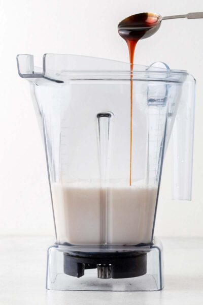 Date syrup poured into a blender with almond milk. 
