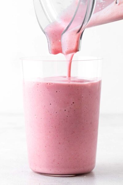 Pouring pink smoothie in a cup.