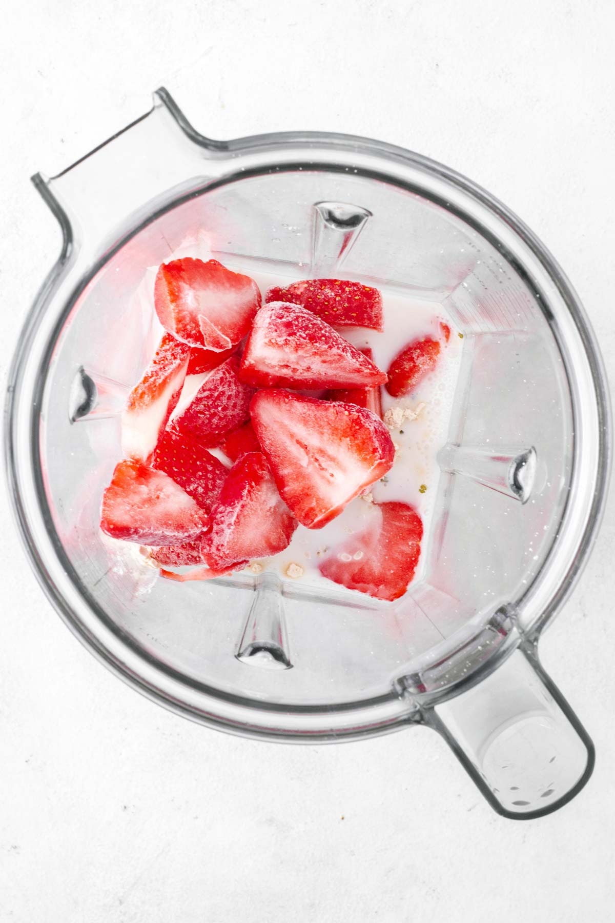Strawberry protein smoothie ingredients in a blender.
