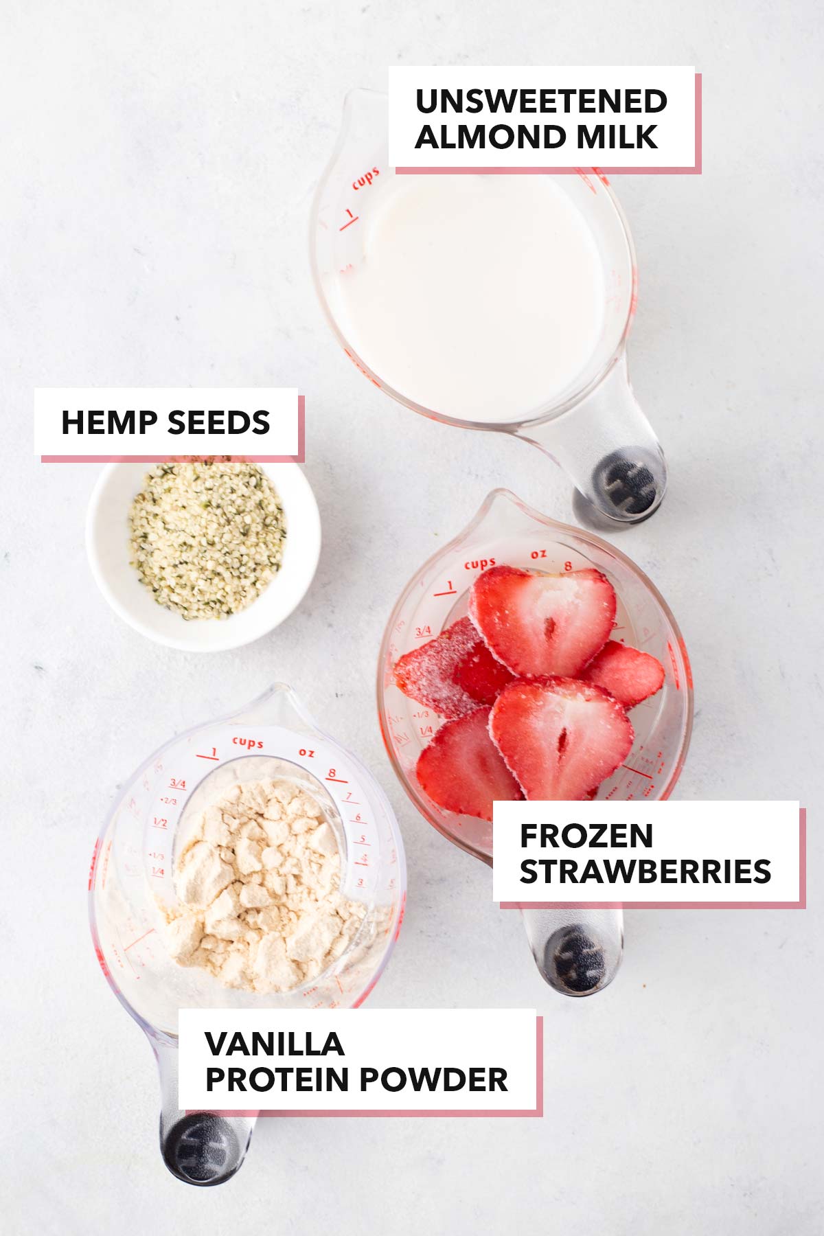 Ingredients for a strawberry protein smoothie bowl on a gray table.