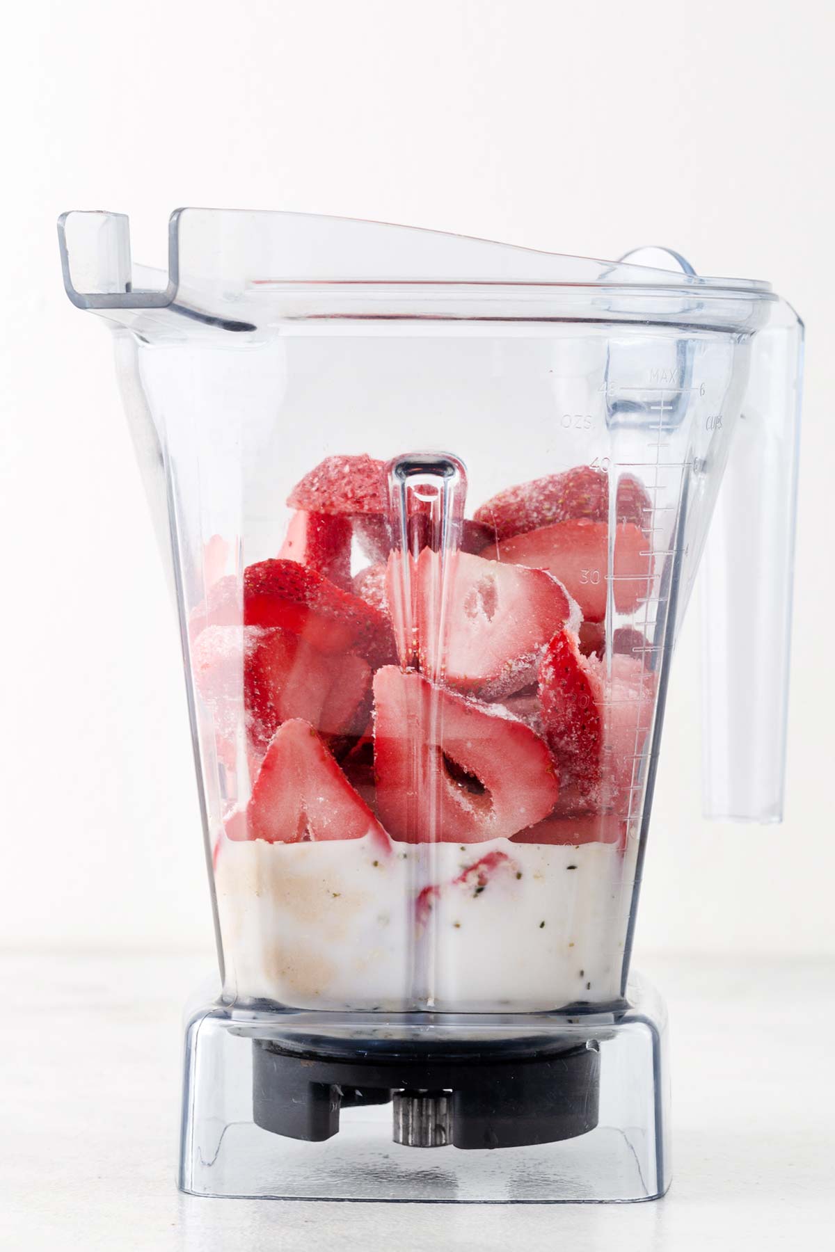 Ingredients for strawberry protein smoothie bowl in a blender.